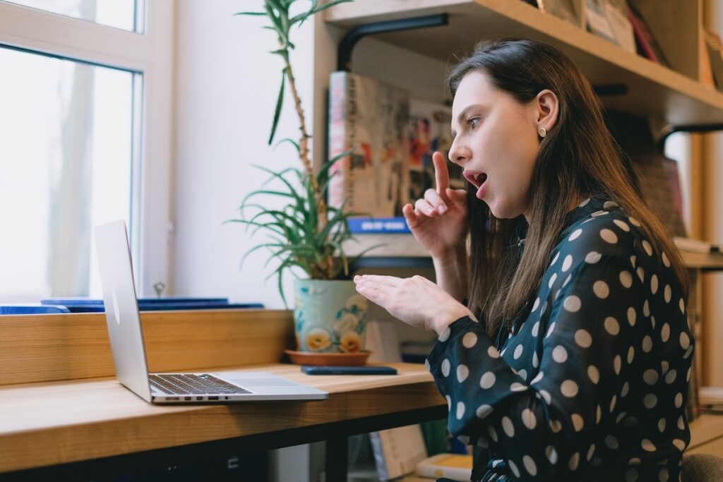 Mulher em ambiente de trabalho com acessibilidade digital conversando em libras por chamada de vídeo em notebook.