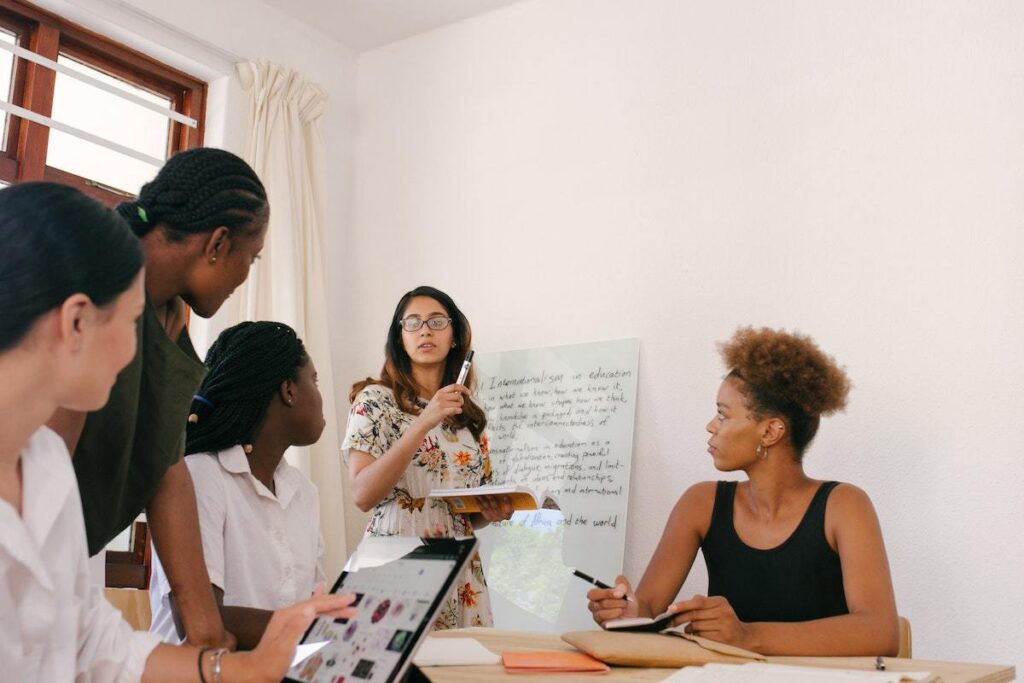 Reunião em ambiente de trabalho com mulheres reunidas e sua líder expõe dados em cartaz durante a mesma