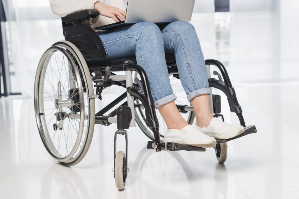 mulher na cadeira de rodas com um laptop no colo