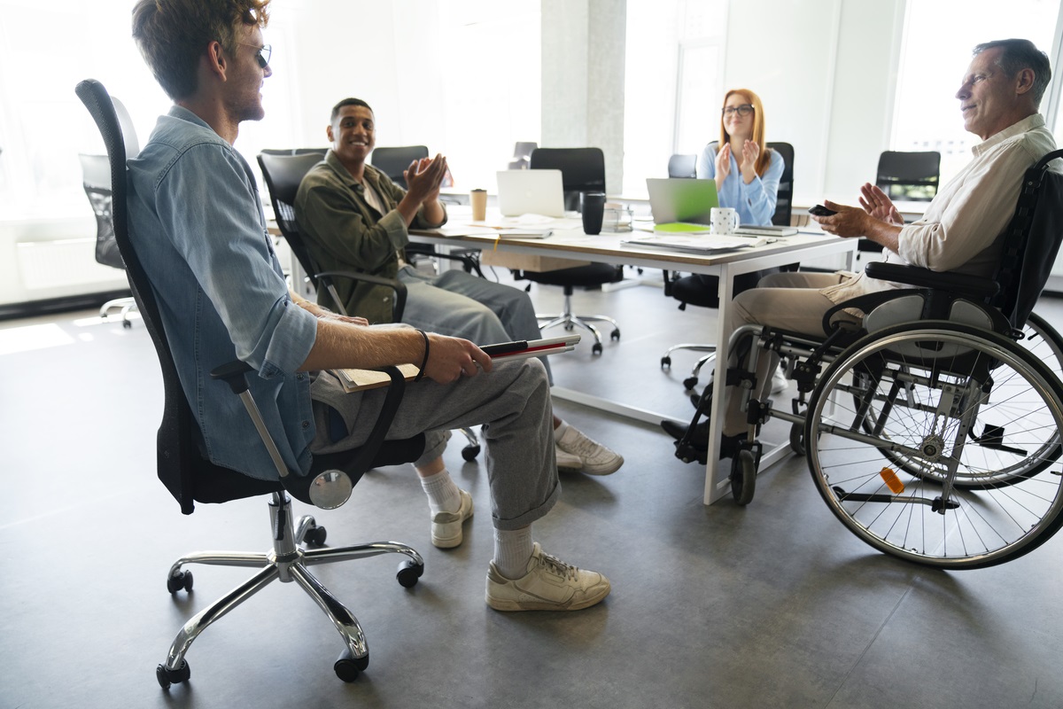 Imagem de pessoas em uma sala, em reunião, uma delas é cadeirante o que indica que a equipe é diversa