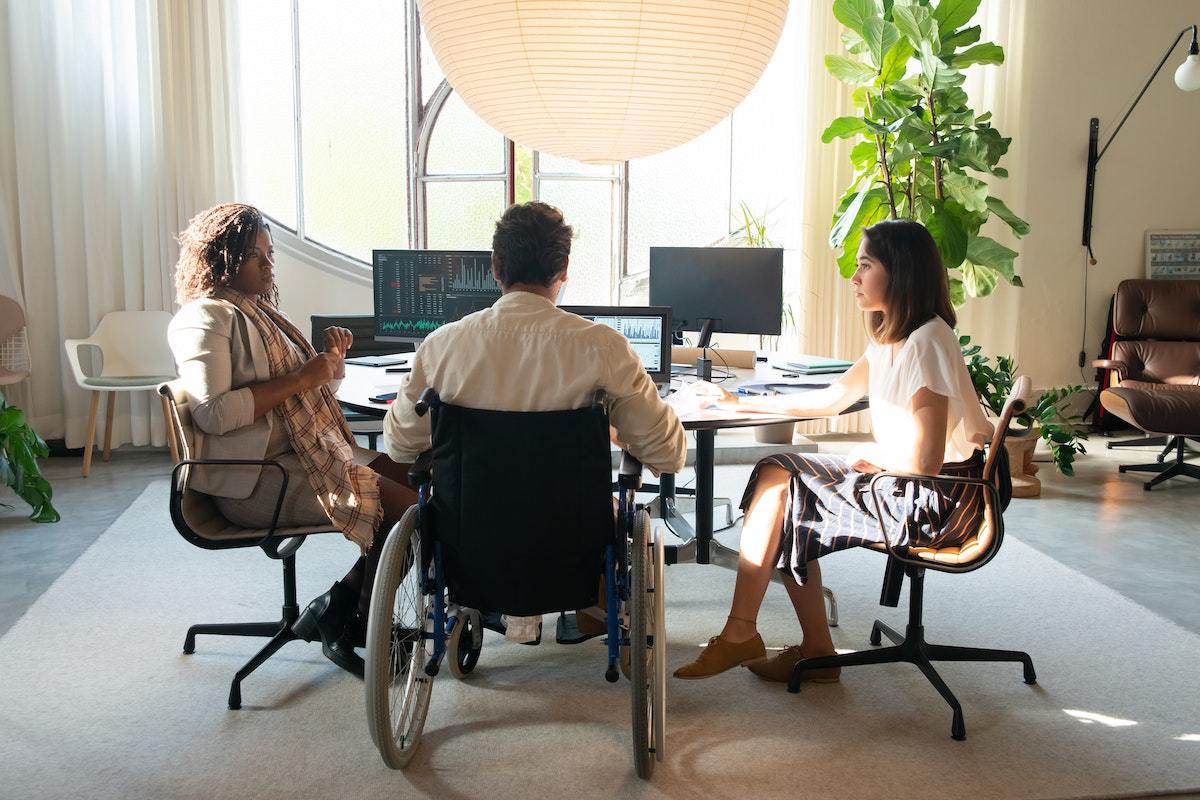 Homem em cadeira de rodas em reunião de trabalho com mulheres