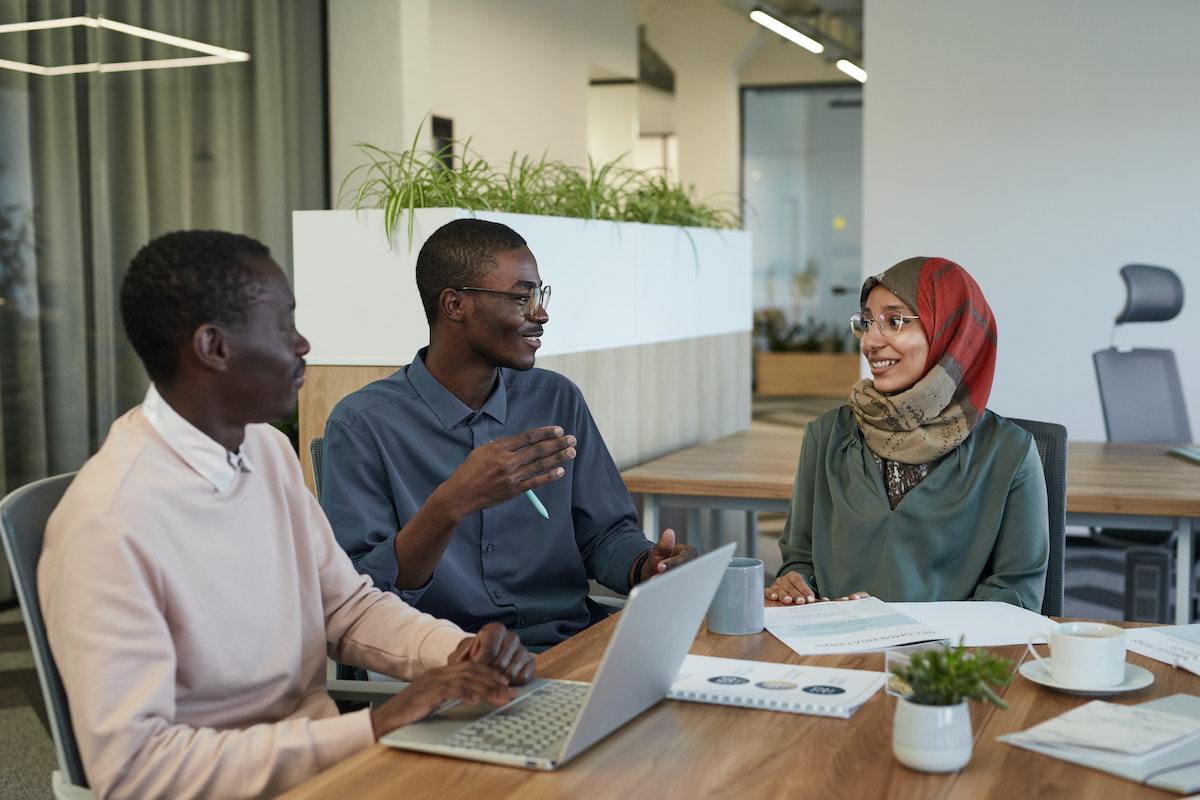 Dois homens e uma mulher conversando em local de trabalho inclusivo