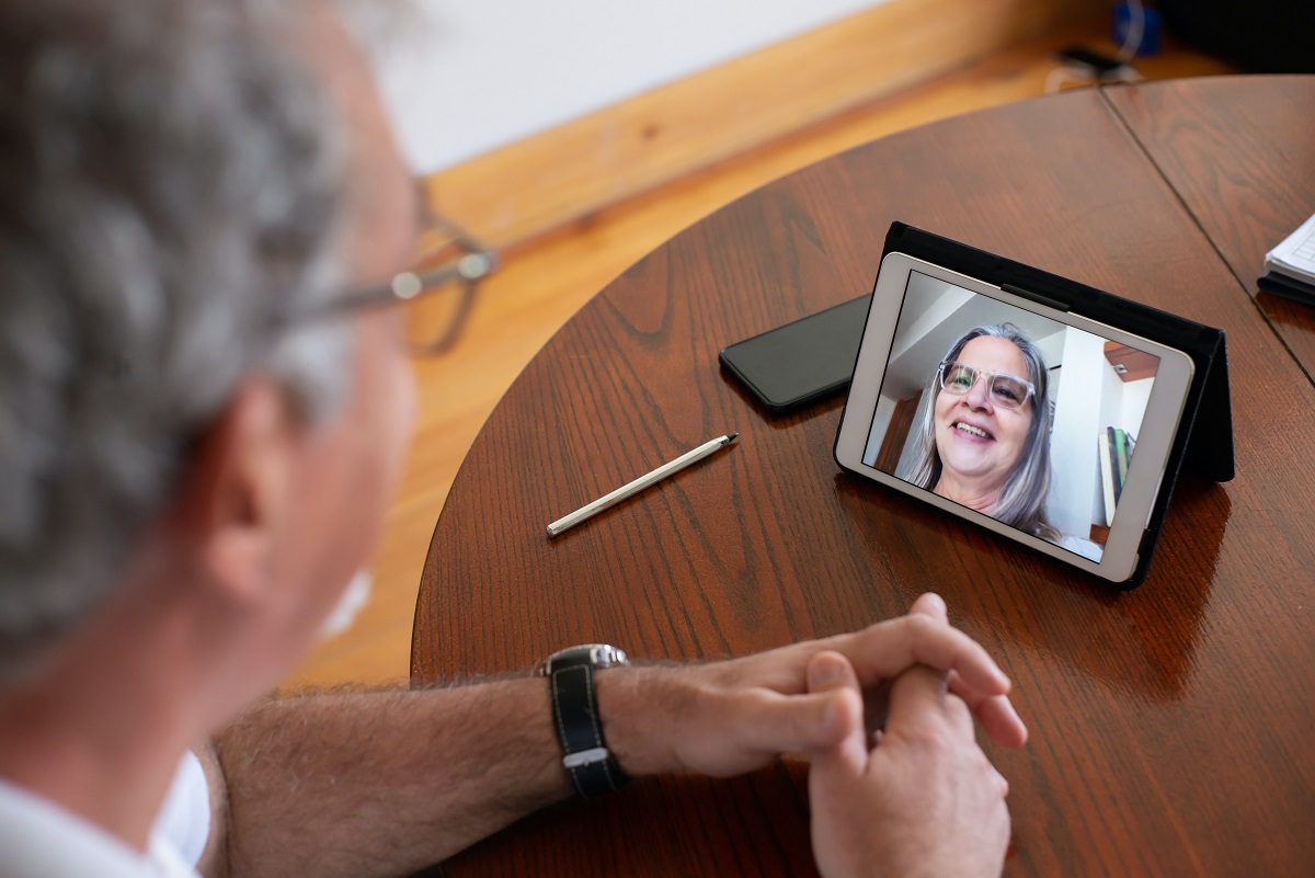 Reunião online com homem e mulher em smartphone sobre mesa de madeira treinando como Aplicar a escuta ativa