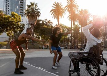 Amigos praticando Plano de inclusão e jogando basquete com homem em cadeira de rodas