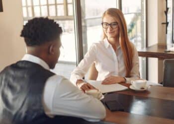 Homem sentado diante de mulher em processo de Recrutamento e seleção em sala de empresa