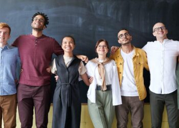 Equipe diversa e inclusiva abraçada de lado a lado em pose para foto em empresa