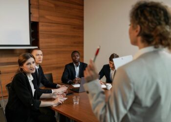 Mulher de pé liderando reunião em empresa e falando sobre Estratégia de inclusão e diversidade no ambiente da mesma