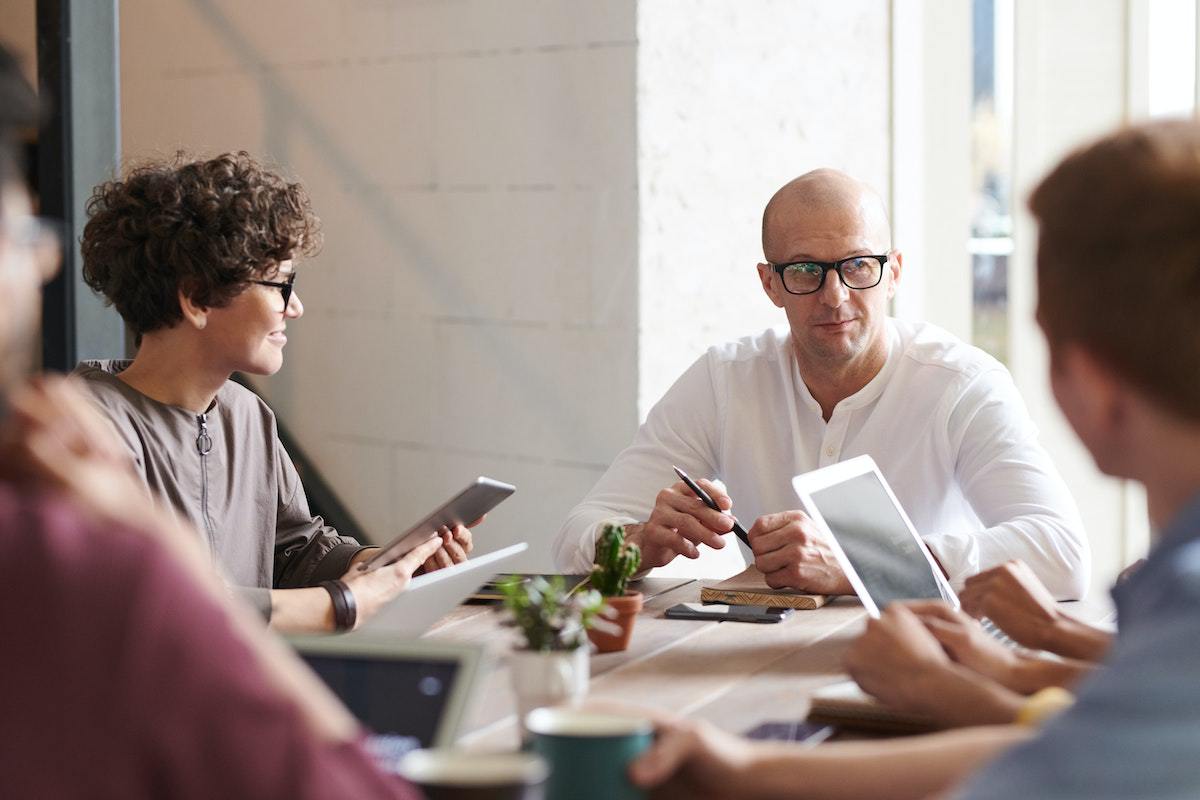 Funcionários inclusivos em reunião ao redor de mesa conversando sobre estratégia