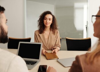 Mulher sentada diante de mesa com homem e outra mulher do outro lado realizando seleção para local de trabalho diverso