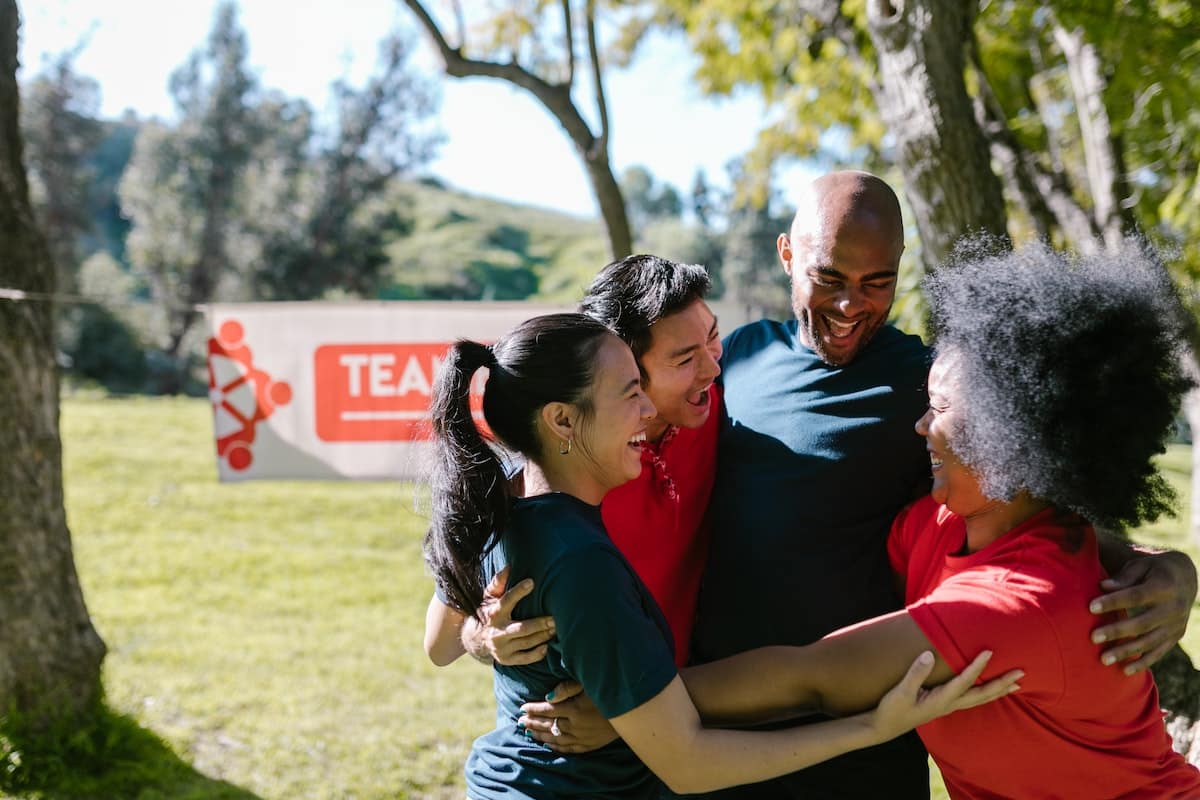 4 pessoas diversas se abraçando e sorrindo