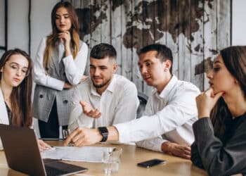 pessoas reunidas na frente de um computador para mostrar como é feito o treinamento de inclusão