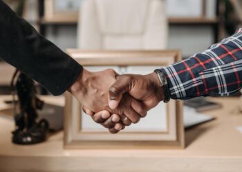 a iamgem ilustra dois homens negros apertando as mãos mostrando um dos exemplos de inclusão nas empresas