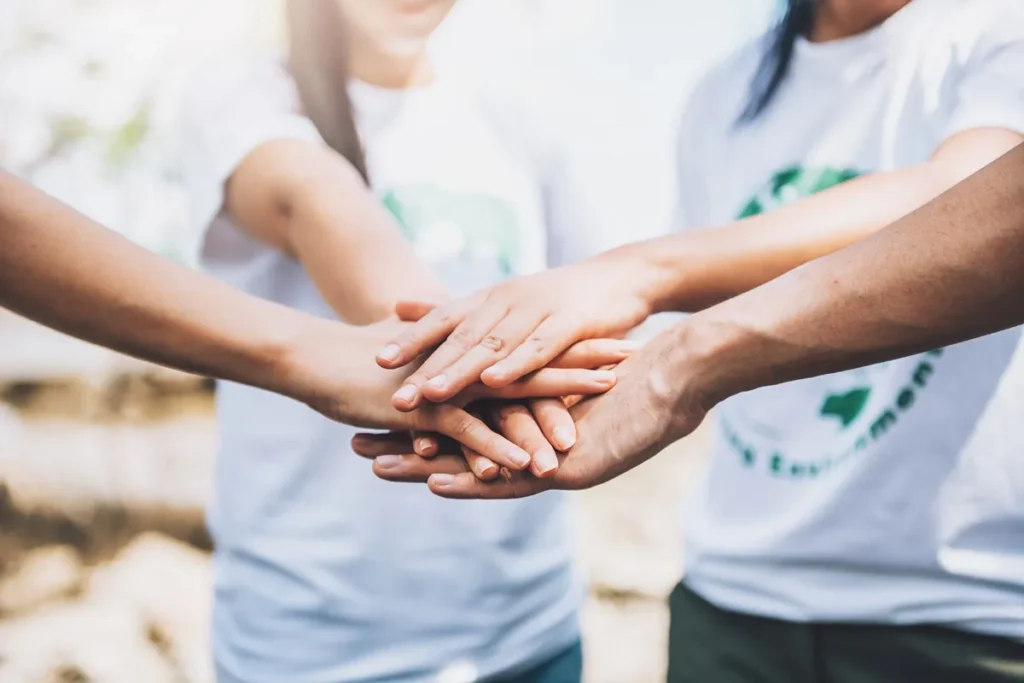 Grupo de pessoas unindo as mãos em sinal de trabalho em equipe e compromisso com a responsabilidade social.