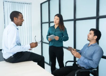 Grupo de três profissionais em uma reunião corporativa, discutindo estratégias e ideias no escritório.