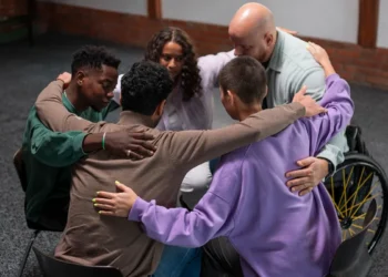 Grupo diverso de pessoas sentadas em círculo, abraçadas em um momento de apoio emocional e inclusão.