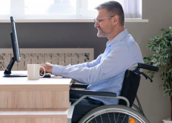 Homem cadeirante trabalhando em frente ao computador em ambiente de escritório moderno