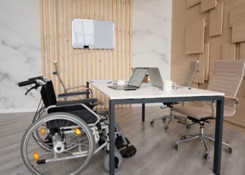 Escritório moderno com cadeira de rodas ao lado de mesa de reuniões com notebooks e cadeiras executivas