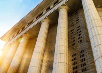 Imagem de um edifício com colunas imponentes, iluminado pela luz do sol, simbolizando força e estabilidade institucional