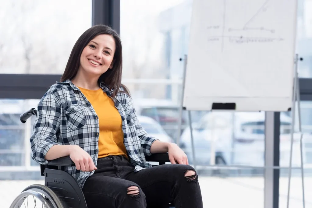 Mulher cadeirante sorrindo em escritório moderno, com quadro de planejamento ao fundo, simbolizando empoderamento e transição de carreira.