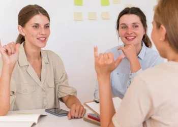 Duas mulheres praticando Libras em uma sessão de estudo, com gestos de comunicação em sinais