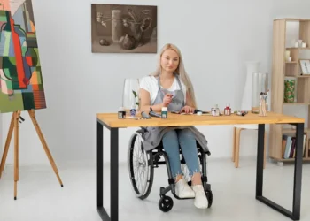 Mulher cadeirante pintando em um ateliê moderno, representando transição de carreira por meio da arte.